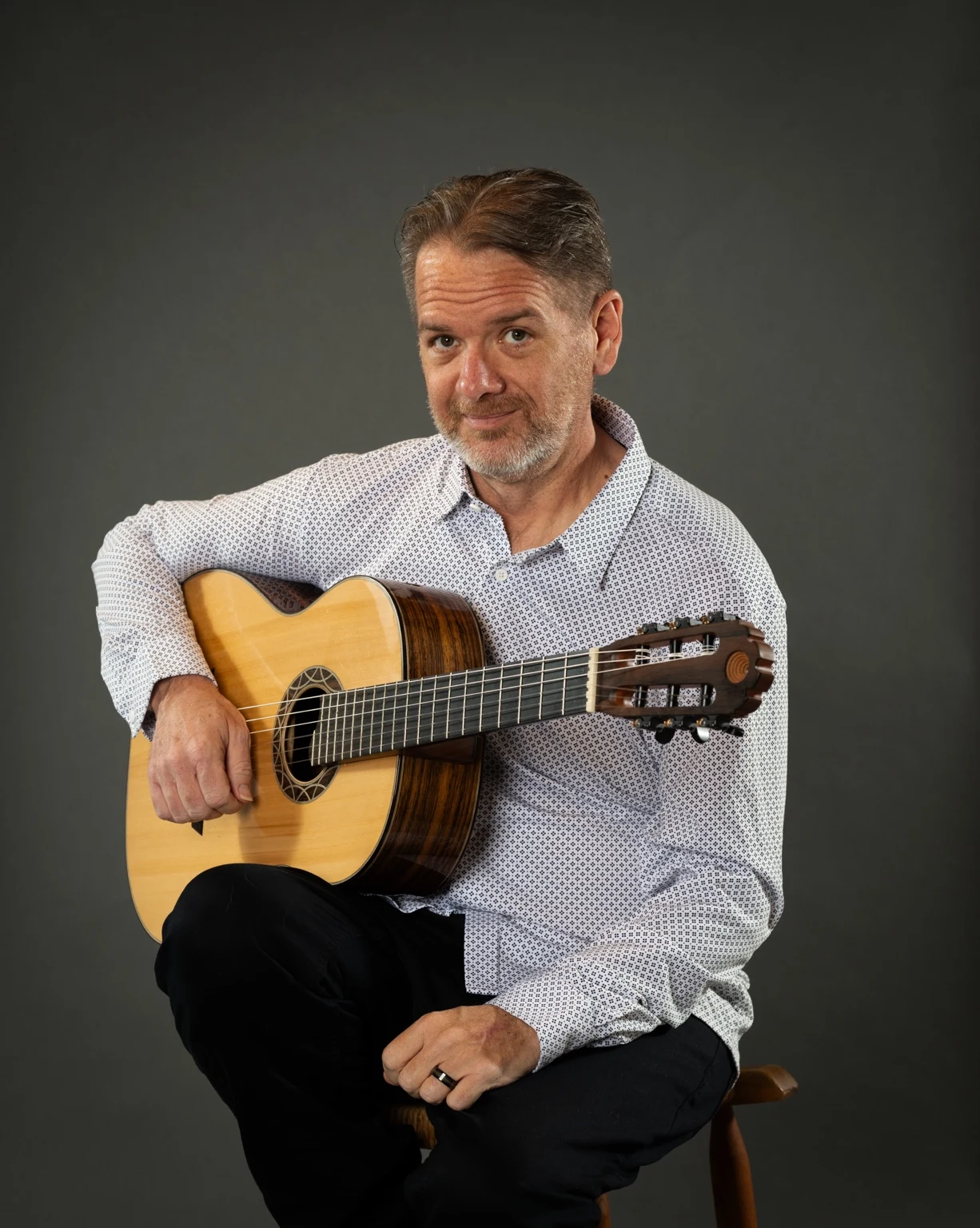 Christopher Gotzen-Berg seated with his classical guitar